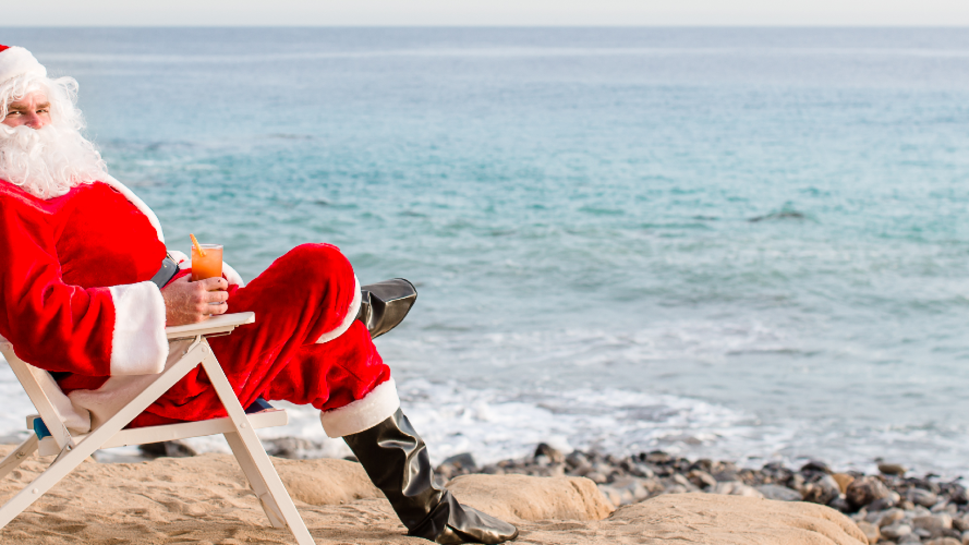 A Person In A Santa Suit Sitting On A Chair By The Water