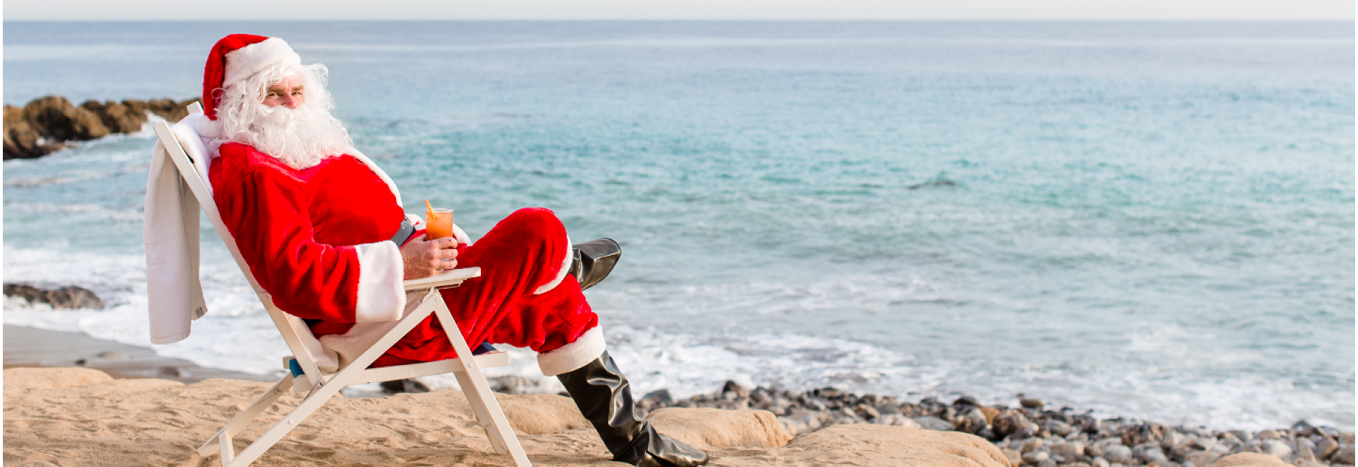 A Person In A Santa Suit Sitting On A Chair By The Water